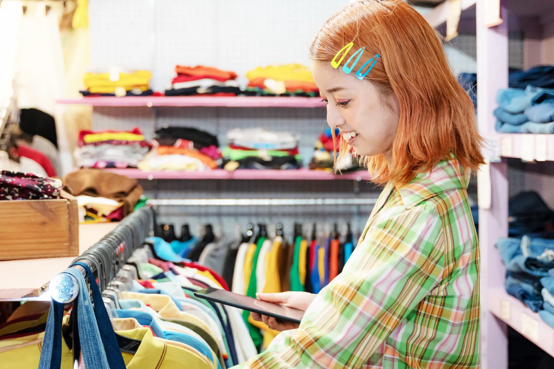 Élève souriante qui participe à la gestion de l’inventaire des vêtements dans une garde-robe collective scolaire.
