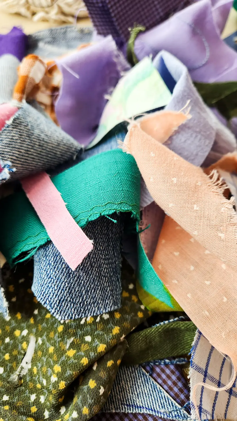 Petites retailles de tissus colorés aux formes et aux textures variées, révélant le potentiel créatif des textiles destinés à l’enfouissement.
